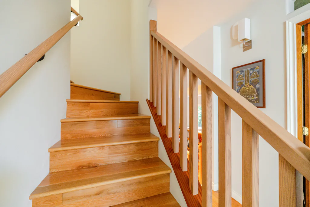 Home interior featuring a polished wooden staircase with light oak handrails and vertical balusters.